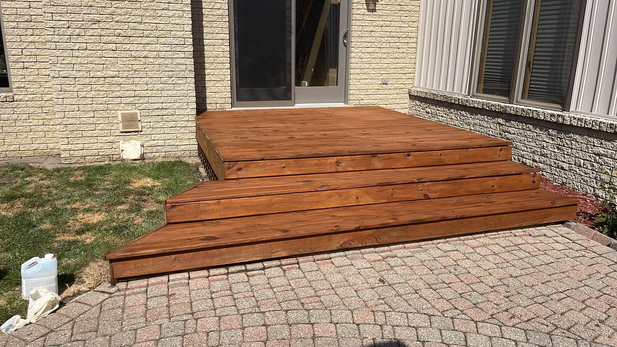 Freshly stained deck steps leading down to a paver patio in Bingham Farms, MI