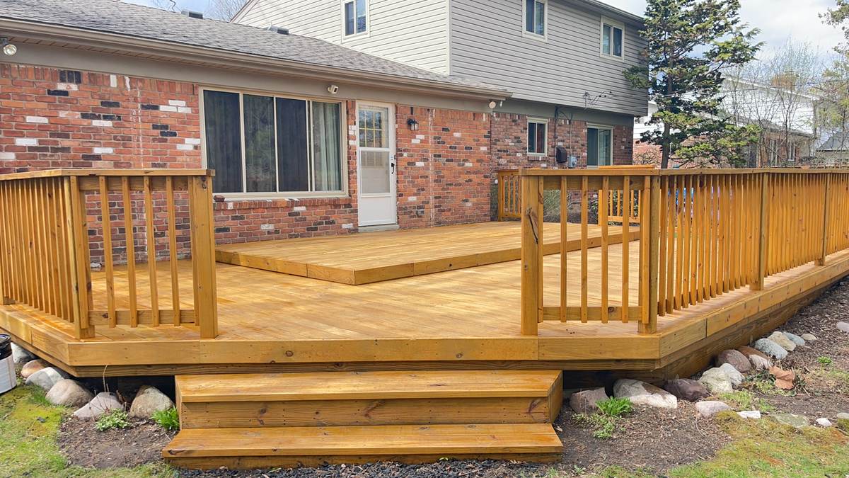 Deck with vinyl railing in a backyard with mulched garden beds in Birmingham, MI