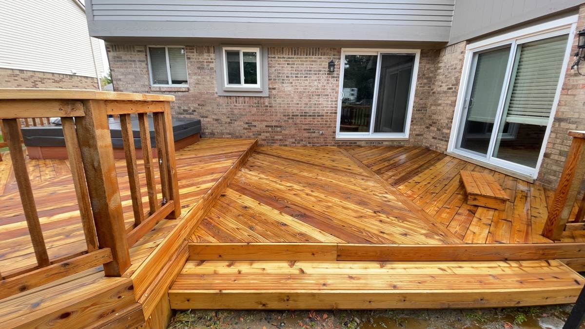 Stained deck with built-in bench seating near a brick home's sliding door in Canton, MI