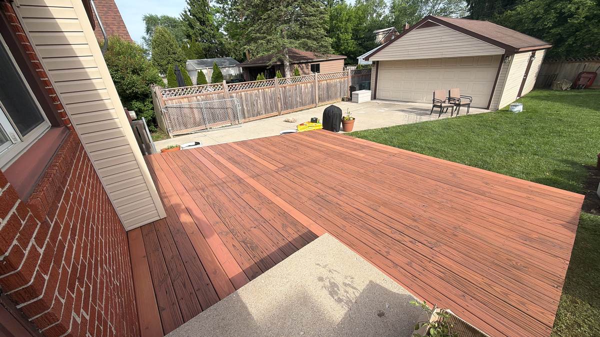 Close-up of stained deck boards near a brick home and garage in Lincoln Park, MI