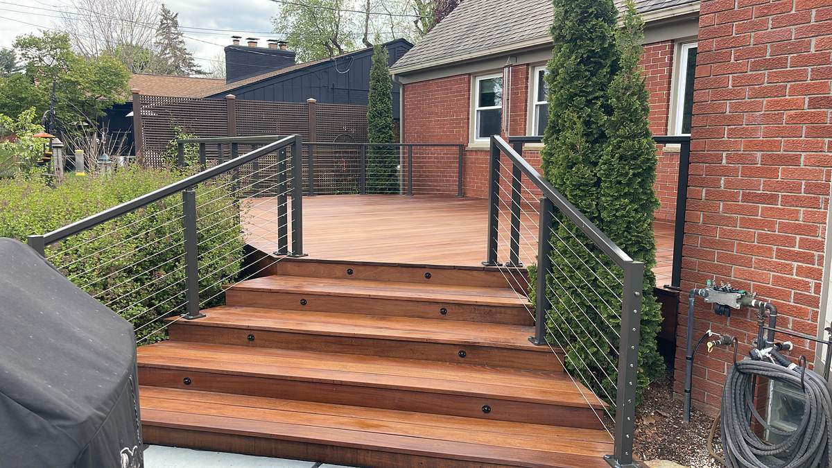 Deck with stainless steel cable railing near a brick home in Northville, MI