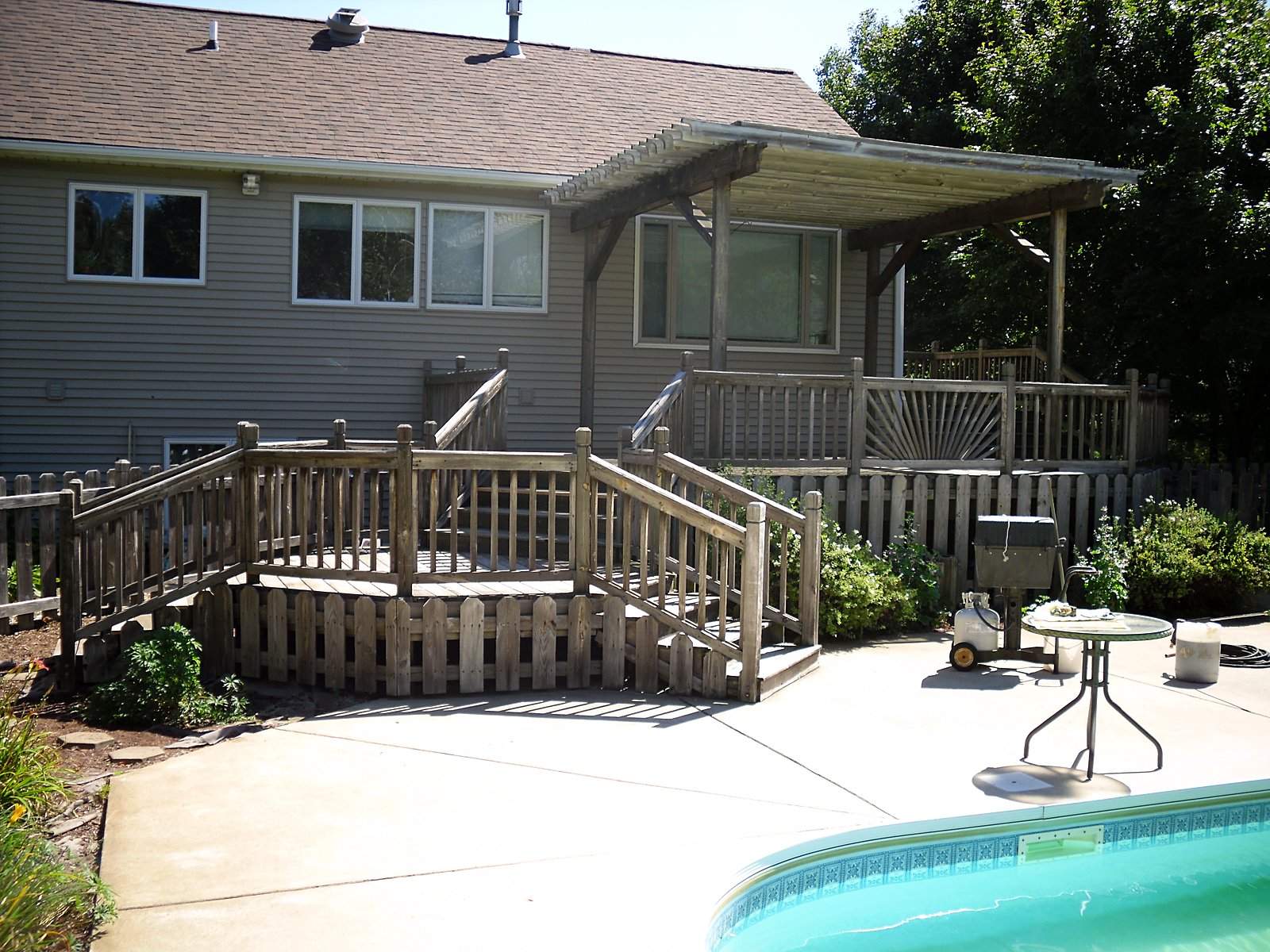 Weathered deck and pergola by the pool, before restoration in Northville, MI