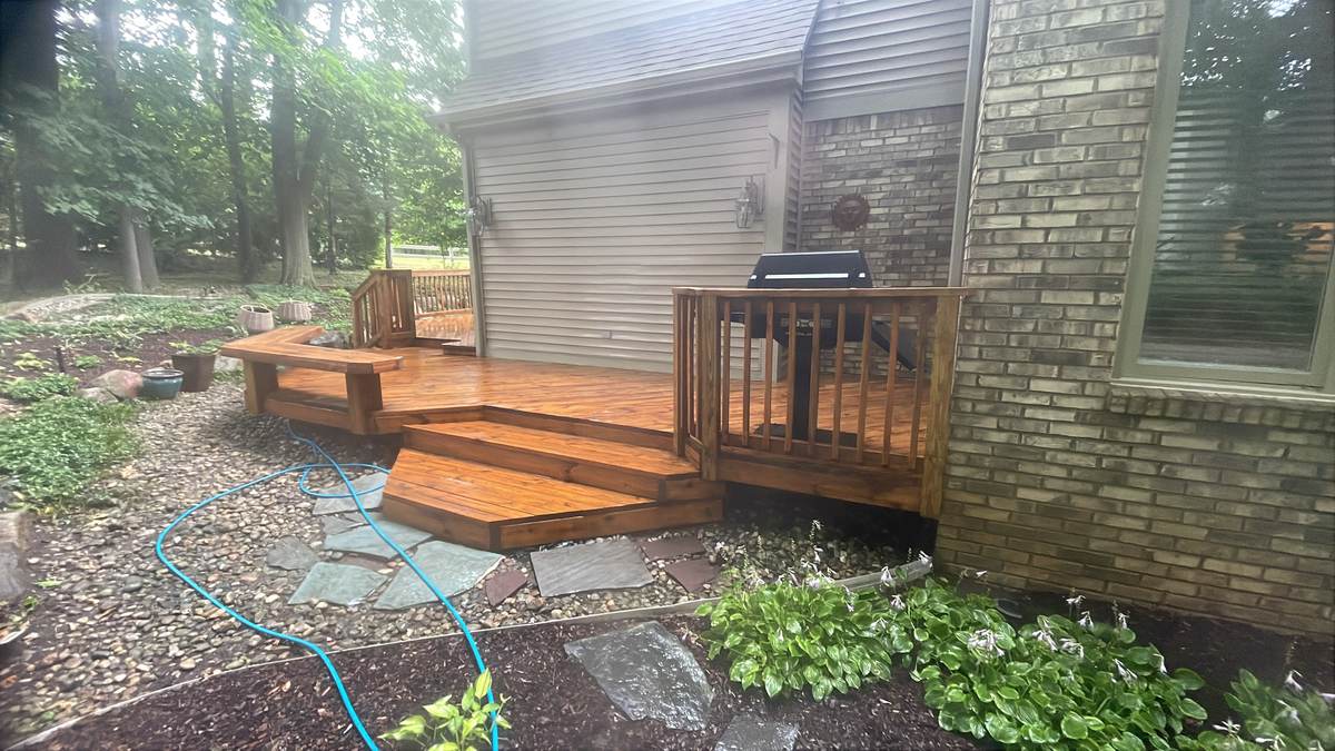 Wood deck with built-in bench seating near a brick home in Oxford, MI