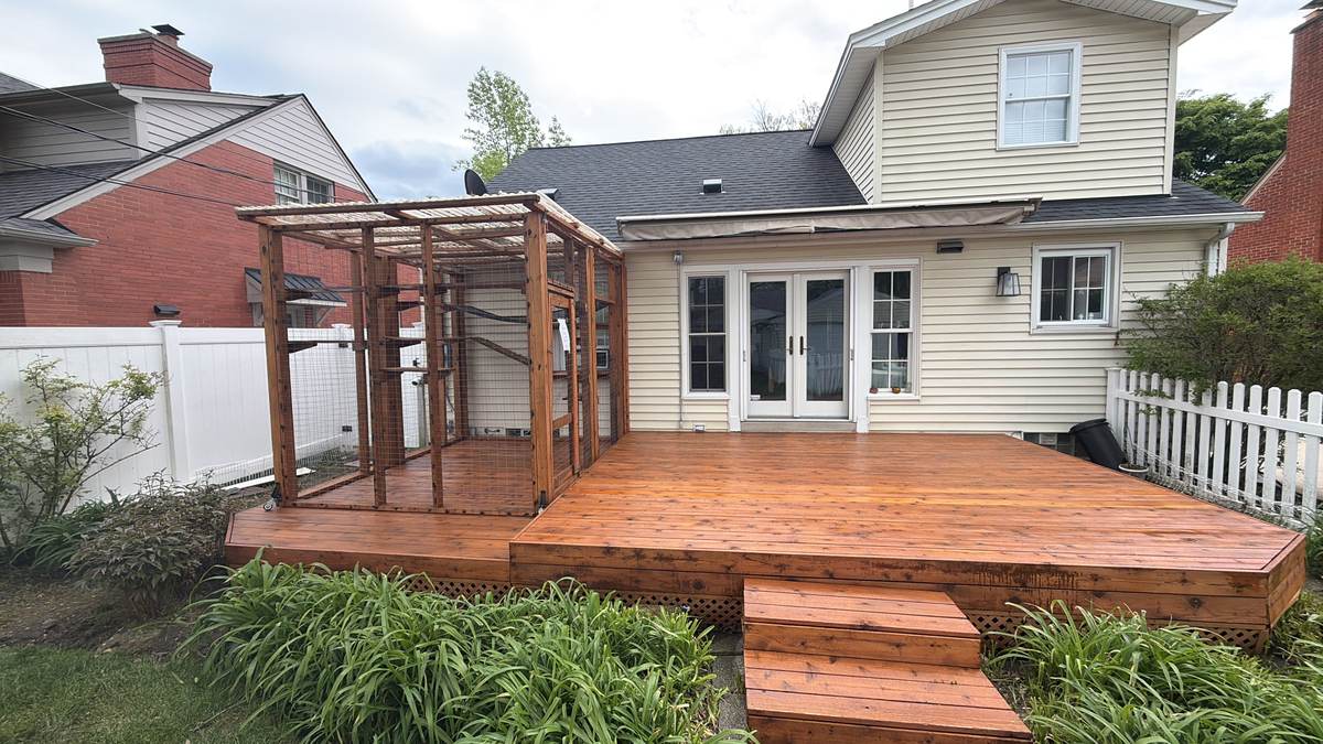 Deck with a new pergola frame under construction near a picket fence in Ferndale, MI